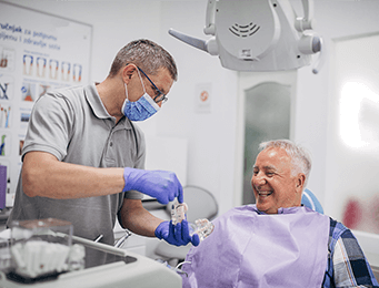 a dentist showing a patient dentures produced by a dental lab that serves the US and Canada